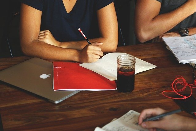 imagem de algumas pessoas em uma mesa com cadernos e um notebook estudando a declaração de previsão de faturamento