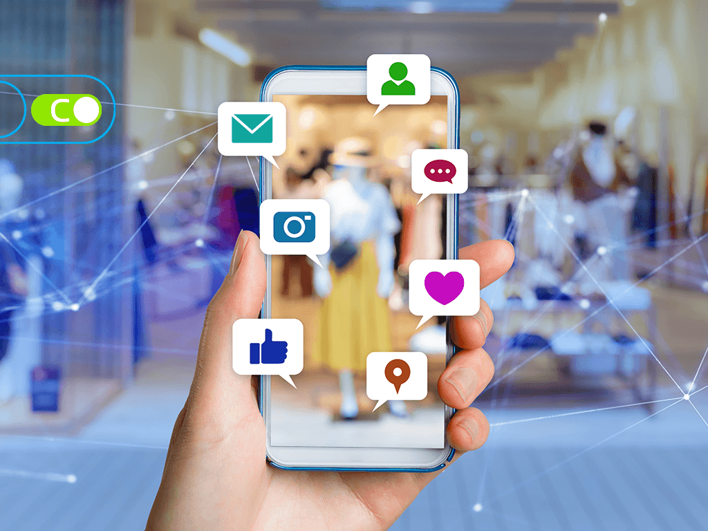 Uma imagem ilustrativa de uma mão segurando um celular, e do celular sai alguns ícones de rede sociais.