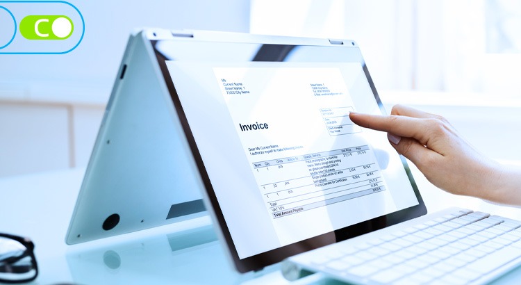 Na imagem há um tablet apoiado na mesa em pé, com uma pessoa o utilizando, em sua tela há um invoice.